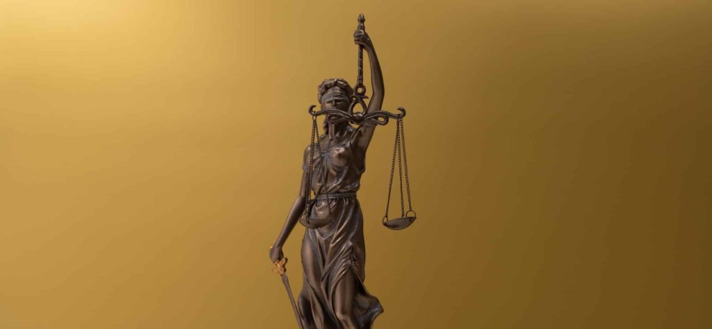 Bronze statue of a woman with scales as the symbol of law and justice on a golden background