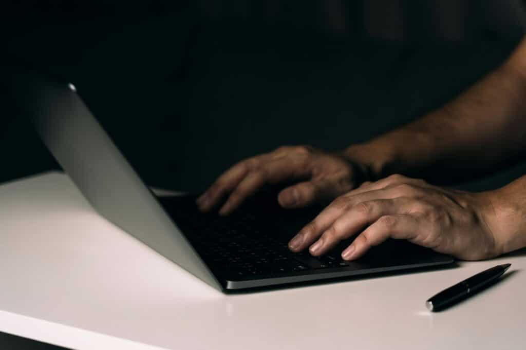 Close up hand using laptop computer on desk.